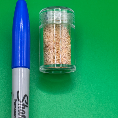 Sharpie permanent marker with blue cap and clear container of brown beads on a green background